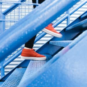 Close up on feet walking up blue steps in the rain in red trainers