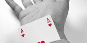 An Ace of Hearts card protruding from the end of a business person's sleeve