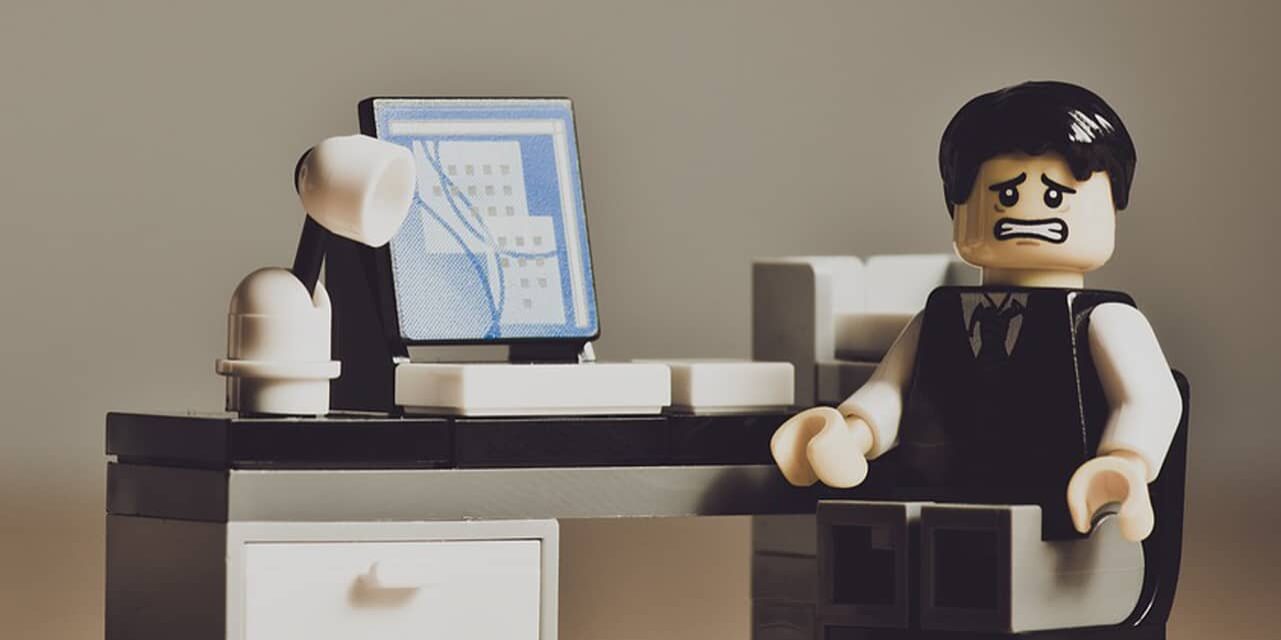 Lego style figure at a desk looking stressed and worried